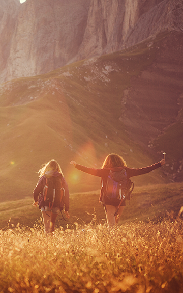 Wanderer gehen im Sonnenlicht auf einer Wiese