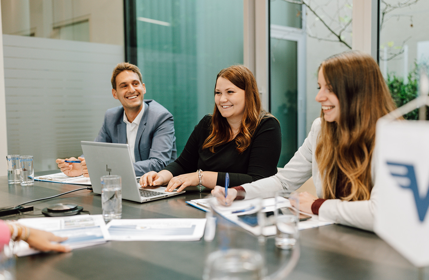 Drei Mitarbeiter sitzen am Tisch und sprechen miteinander