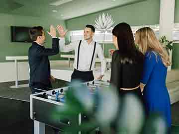 Mitarbeiter stehen beim Tischfussball