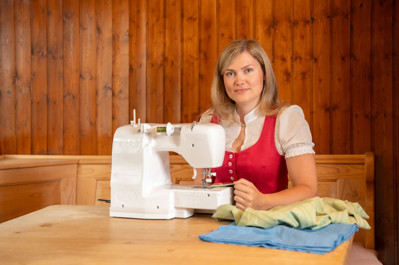 Mitarbeiterin im Dirndl an Naehmaschine