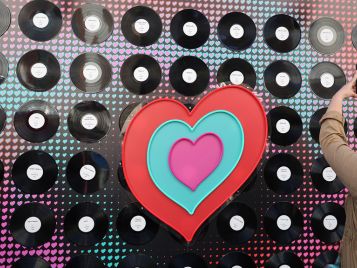 Das Eurovision Song Contest Logo in Herzform vor einer Wand aus Schallplatten.