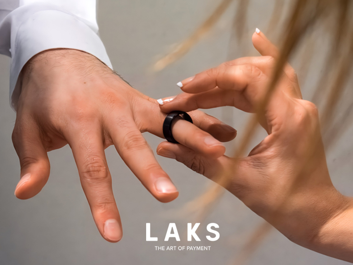 Auf oragenem Hintergrund sieht man den LAKs PAY Ring, wie er an einem Bezahlterminal zahlt.
