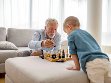 Ein älterer Mann spielt mit einem Kind Schach.